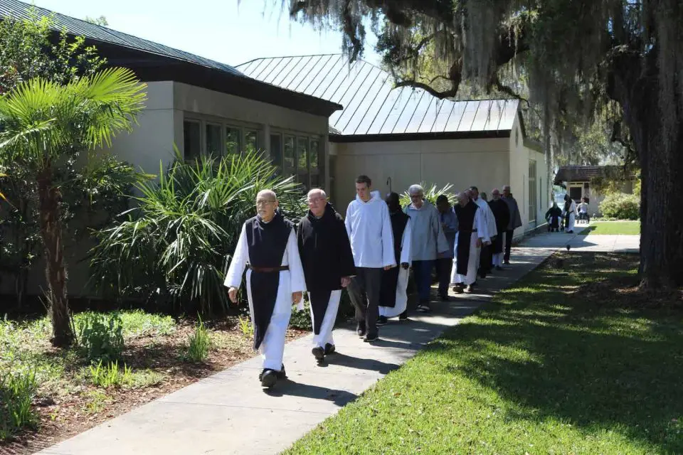 Monks walking outside near a building and trees.