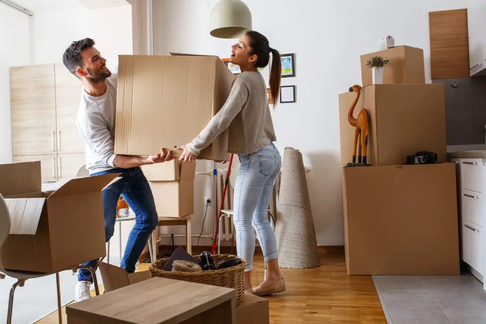 couple carrying moving box