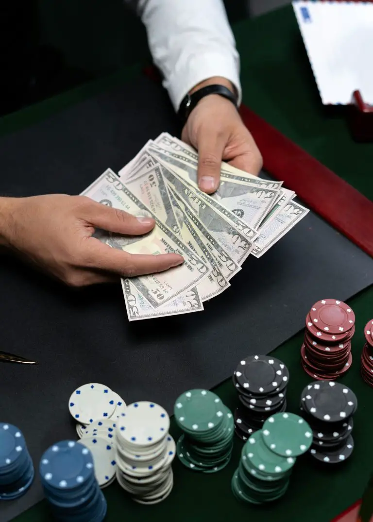 Person holding cash near poker chips on table.