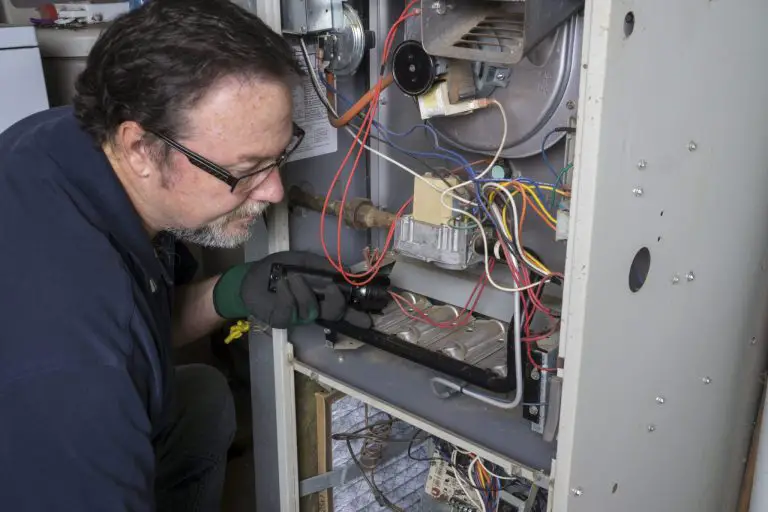 Technician inspecting furnace wiring for maintenance.