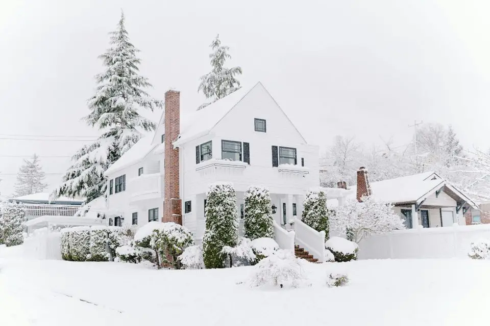 Snow-covered house with evergreen trees.