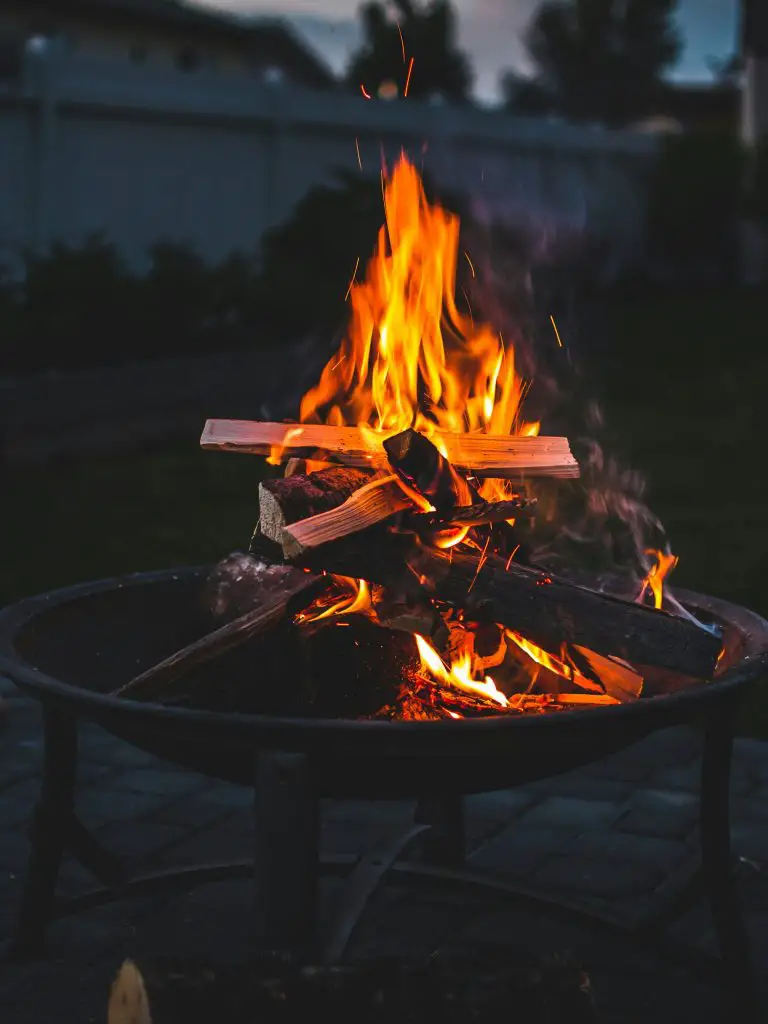 Backyard fire pit with bright flames at night.
