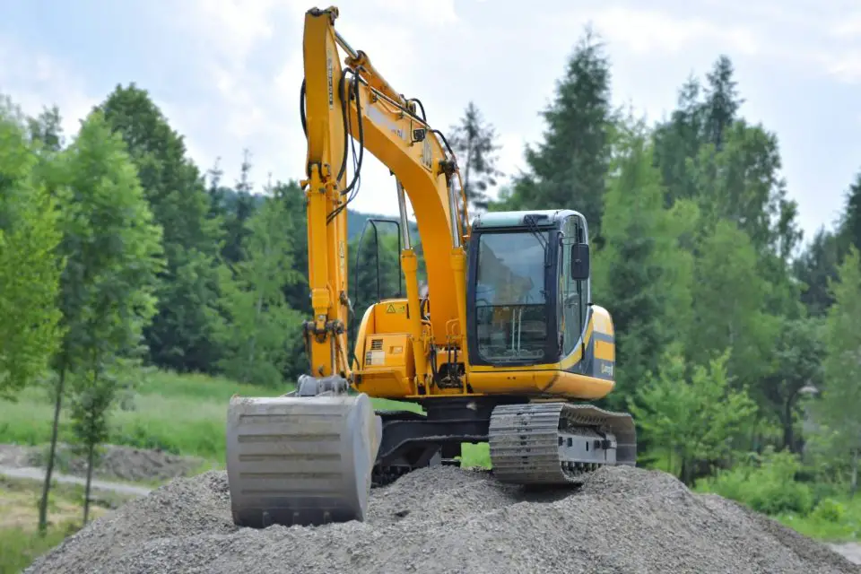 Yellow excavator on a gravel hill in forest