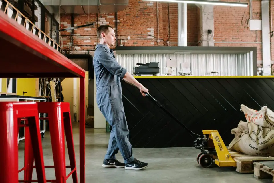 Warehouse worker operating a pallet jack indoors.