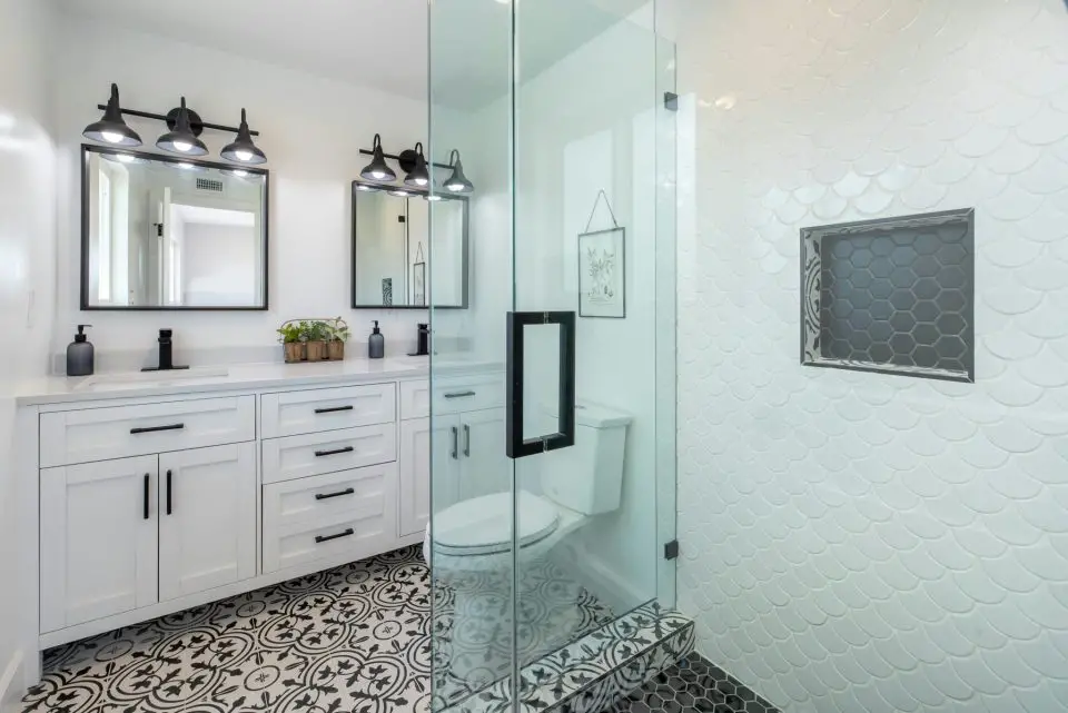 Modern bathroom with glass shower and patterned tiles.
