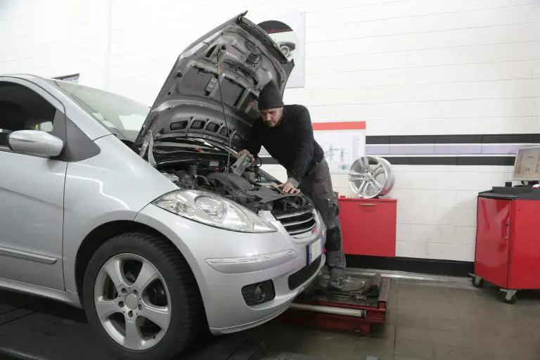 Mechanic inspecting car engine in garage
