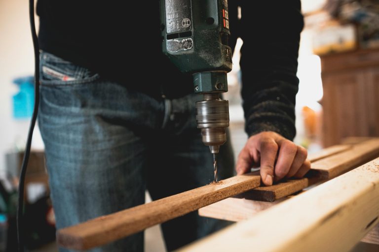 Person drilling a hole in wooden plank.