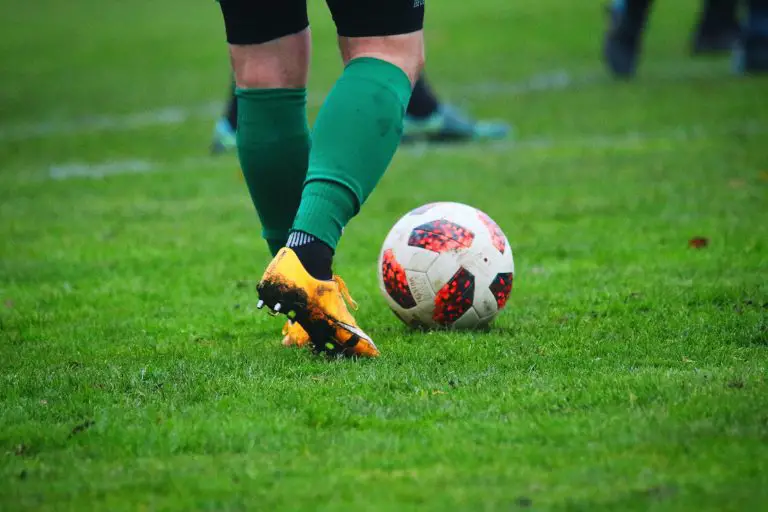 Soccer player kicks ball on grassy field