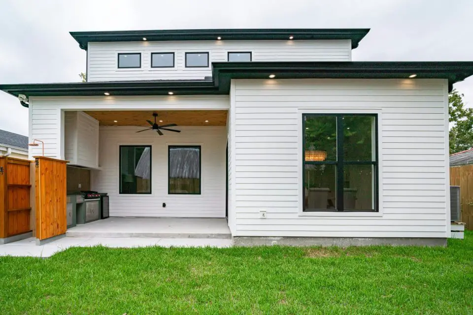 Modern backyard with white siding, patio, and lawn.