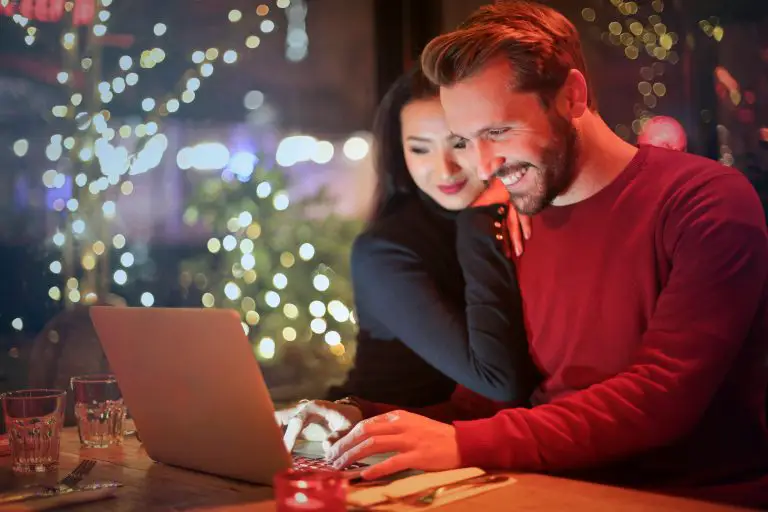 Couple enjoying laptop in festive setting.