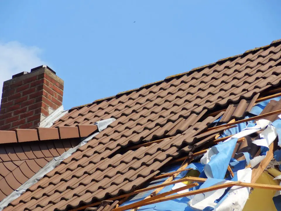 Damaged roof with broken tiles and debris.