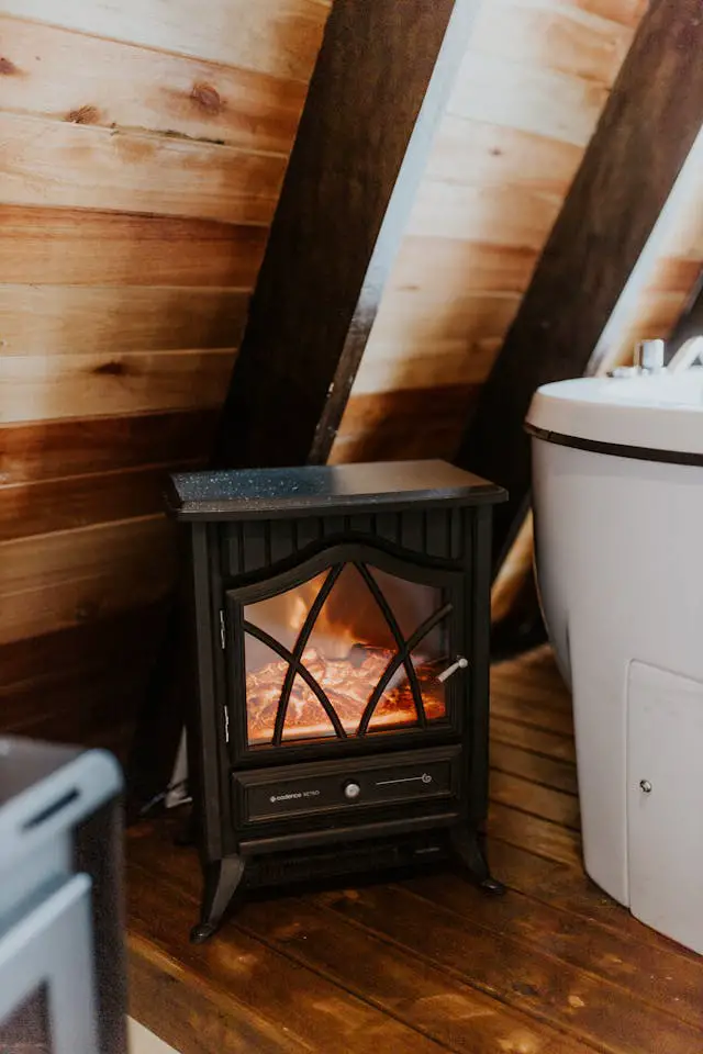 A small vintage-style stove fireplace in a wooden interior, creating a warm atmosphere.