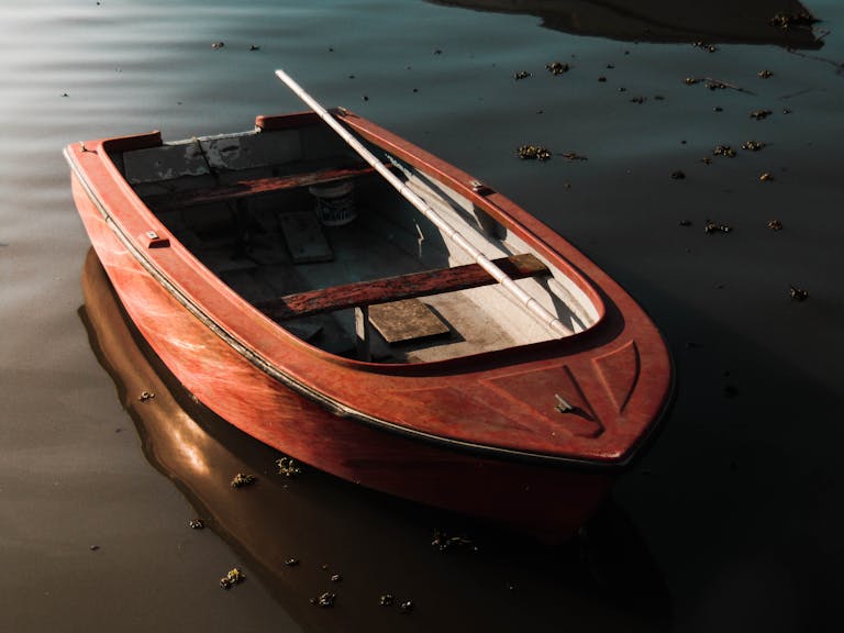 A solitary wooden rowboat floating on a calm lake, capturing a serene and peaceful scene.