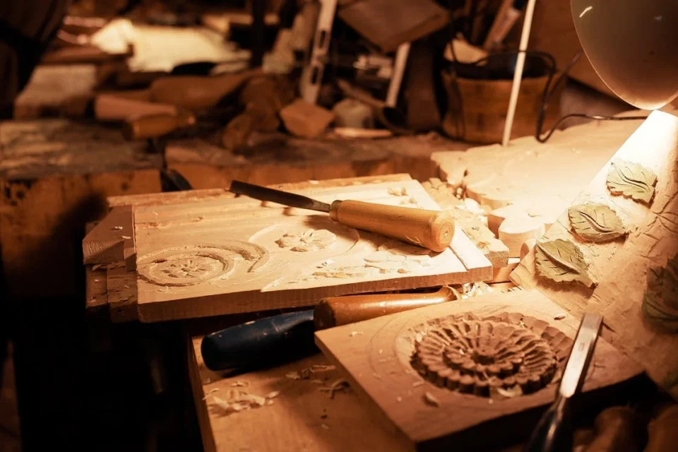 Wood carving tools and designs on workbench.