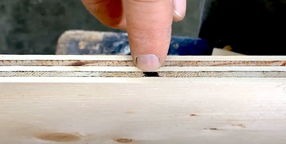 Finger pointing at plywood edge layer.