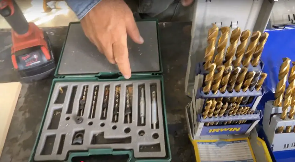 Drill bit sets with drill and person's hand.