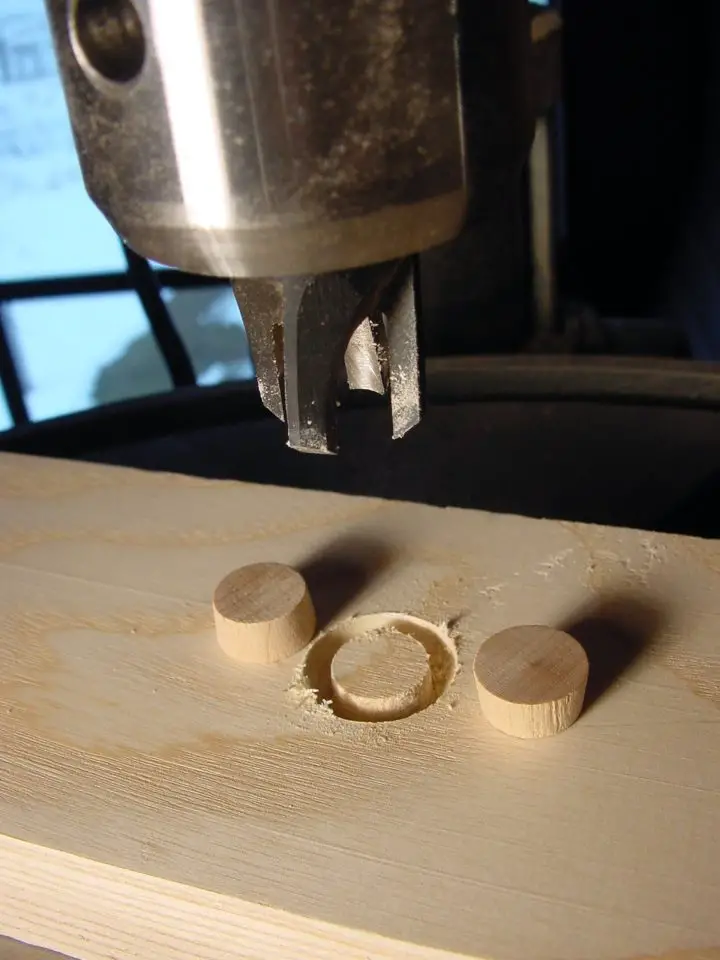 Drill creating wooden plugs on board