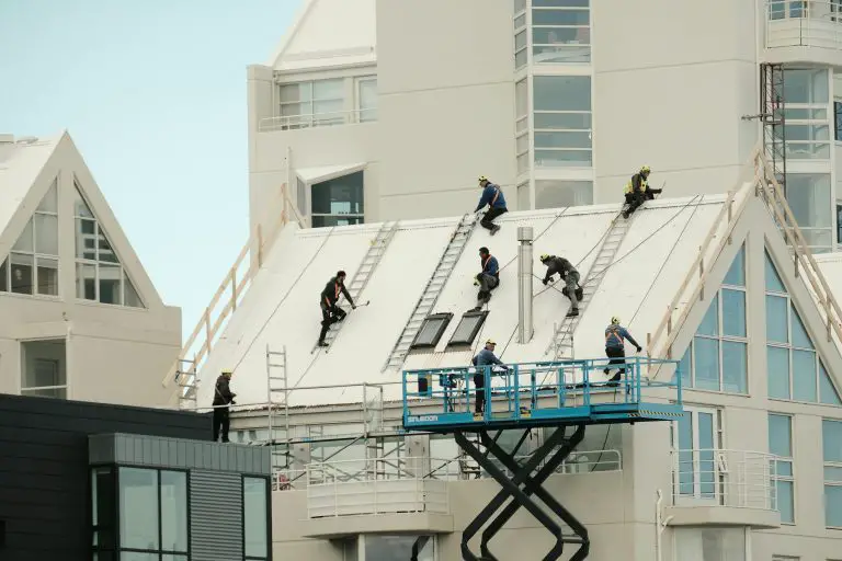 Workers installing roof on modern building.