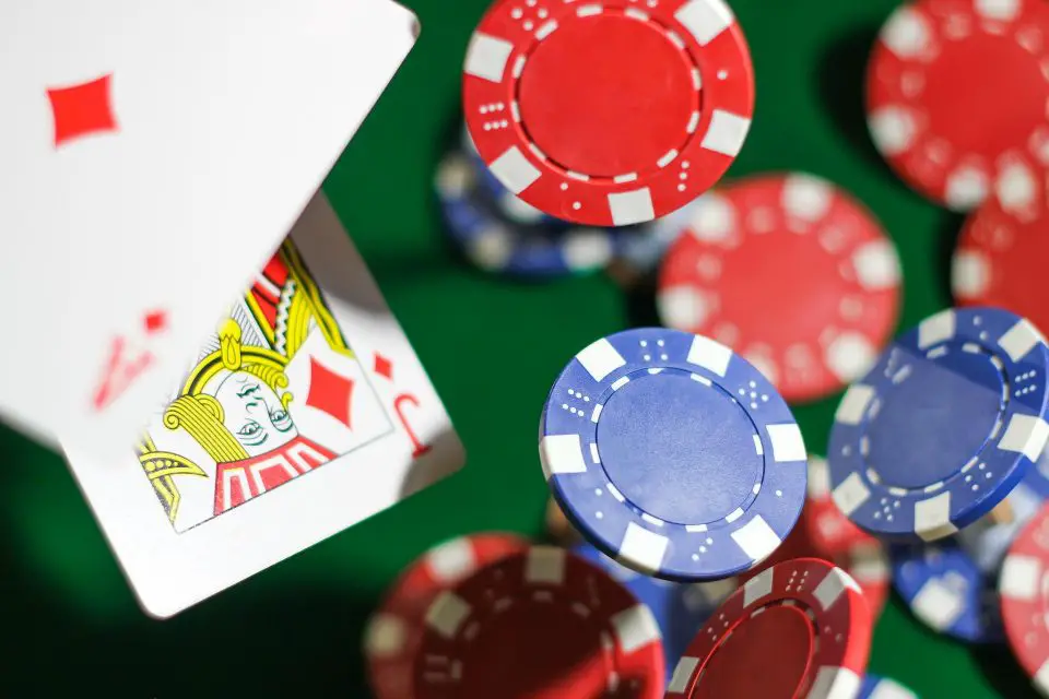 Poker chips and playing cards on green table