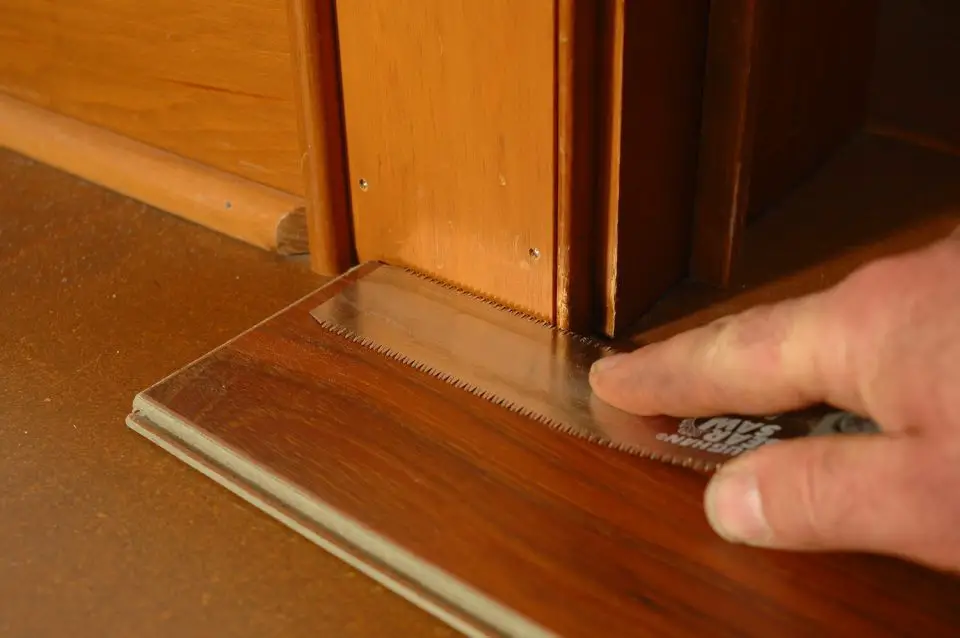 Person measuring wood flooring with a tool.