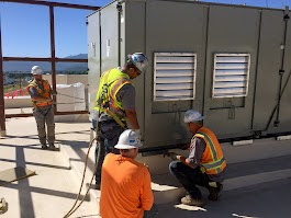 Workers installing large HVAC unit on rooftop