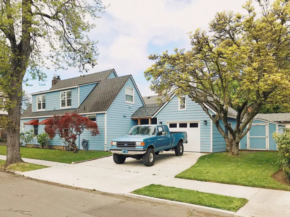 Blue house with truck in driveway, green lawn.