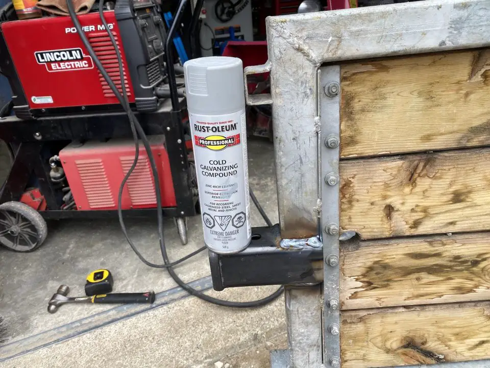 Steel gate welded, galvanized spray and tools visible.