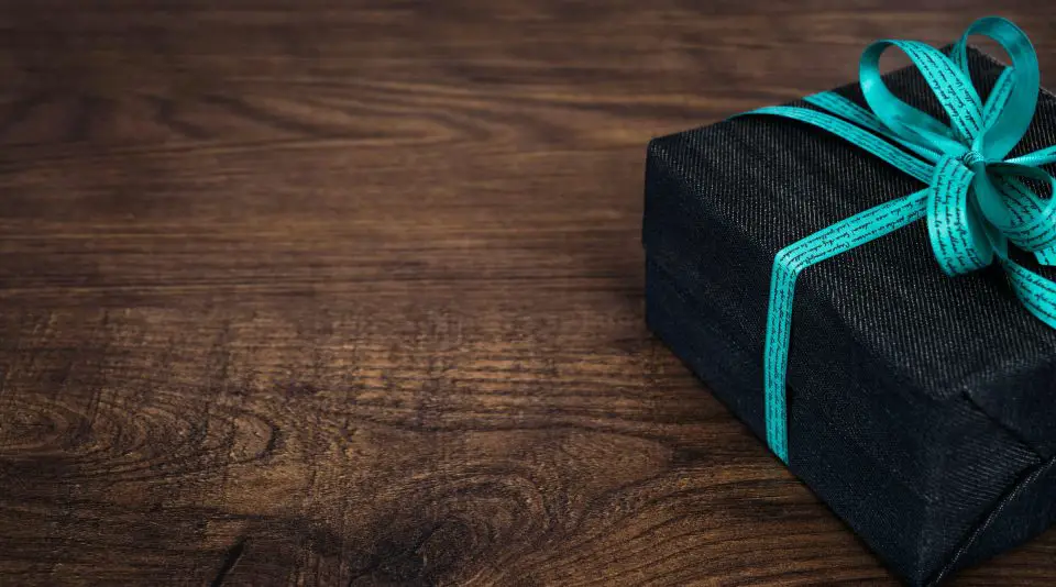 Gift box with teal ribbon on wooden table