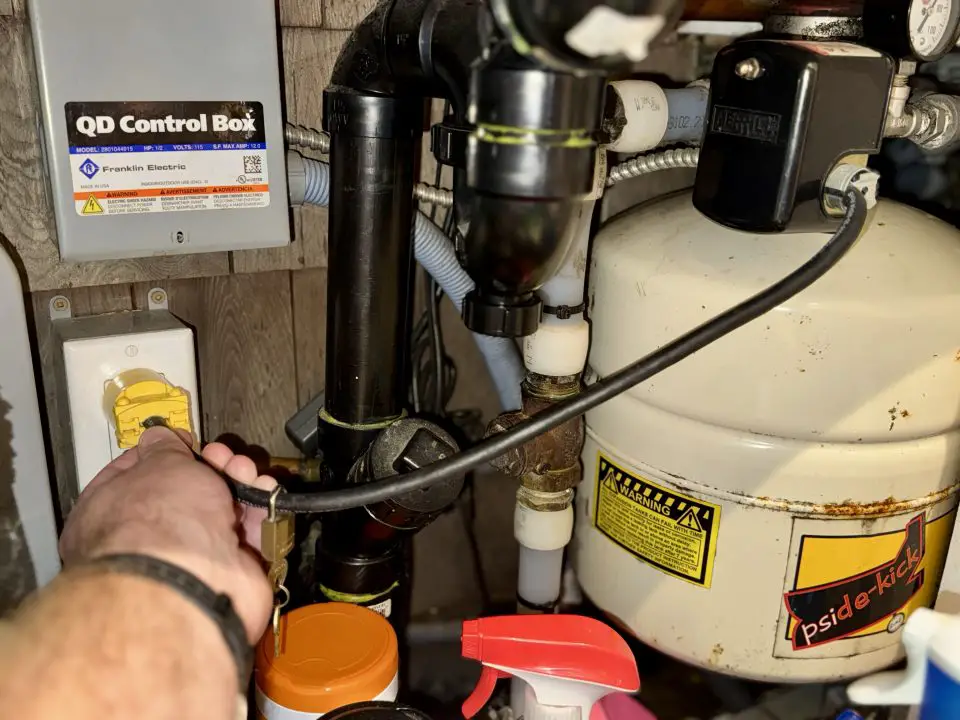 Hand plugging cable in control box near tank.