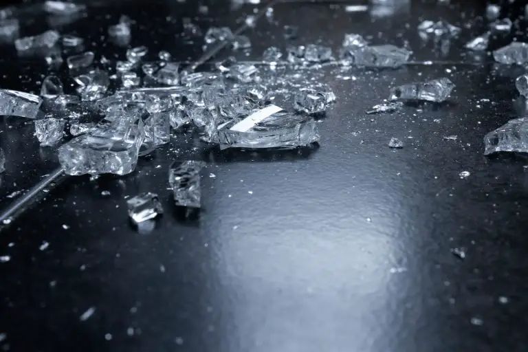 Shattered glass scattered on dark floor.