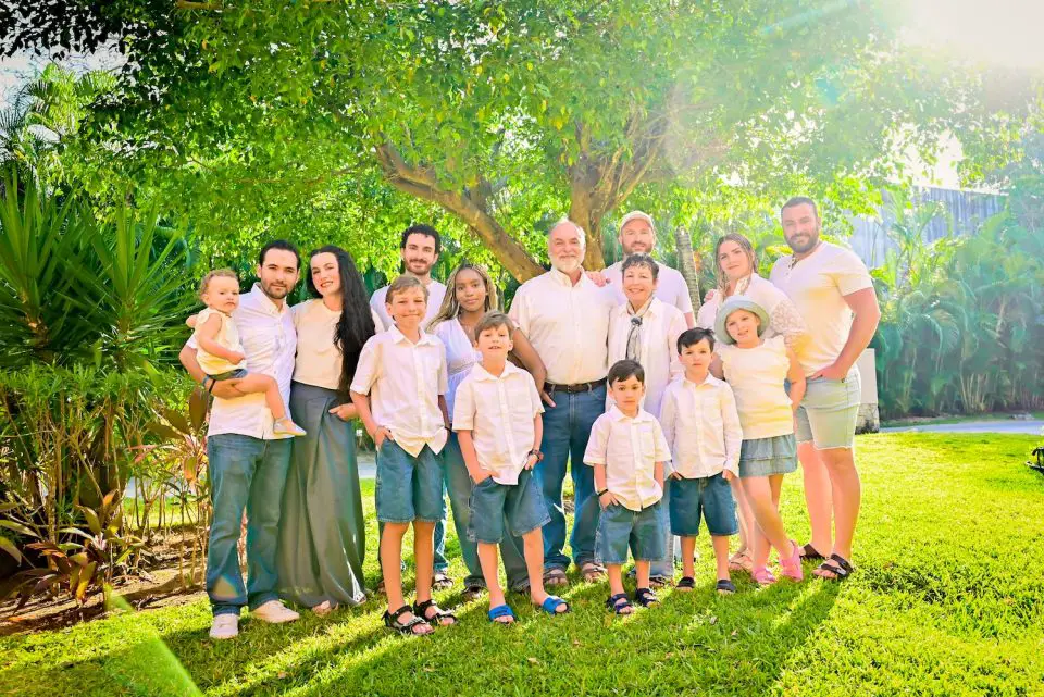 Large family posing outdoors in sunny garden.