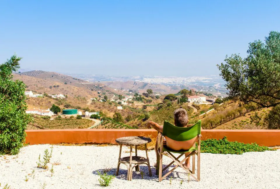 Person relaxing in chair, overlooking scenic countryside view.