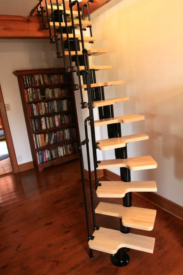 Wooden spiral staircase in a library room.