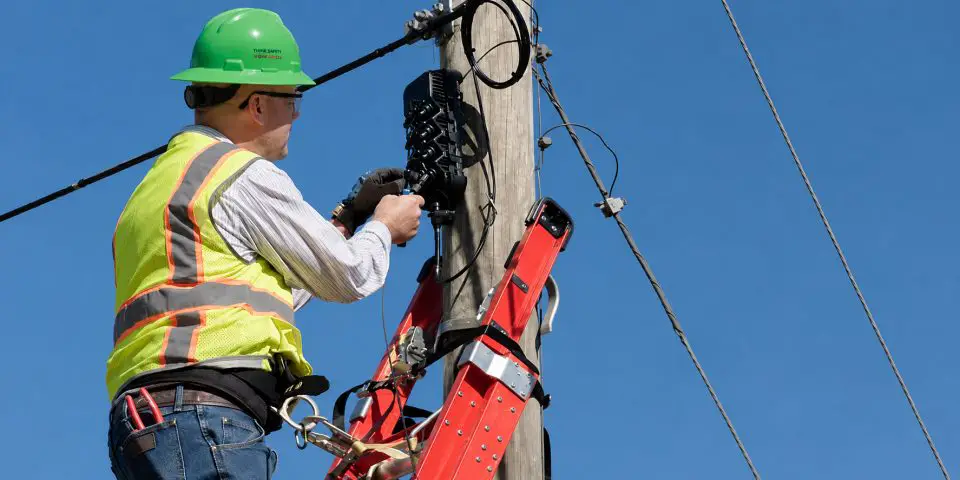 Worker on ladder repairing overhead cable connections.