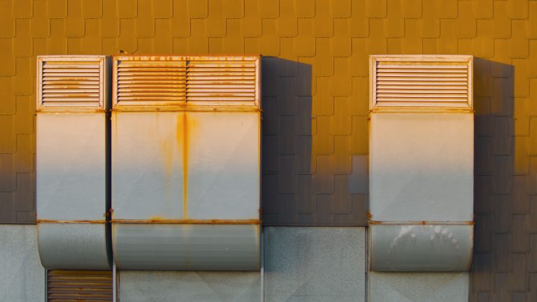 Three rooftop ventilation units with rust stains.