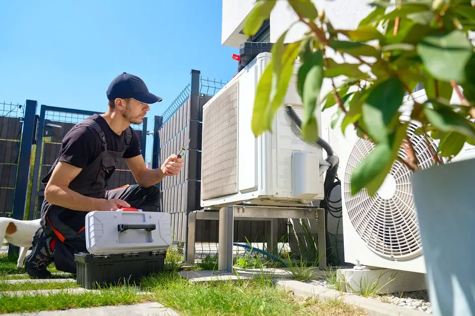 Technician repairing outdoor air conditioning unit.