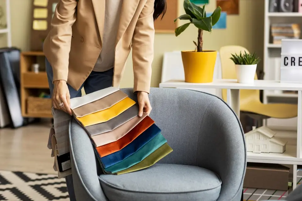 Person displaying colourful fabric swatches on chair.