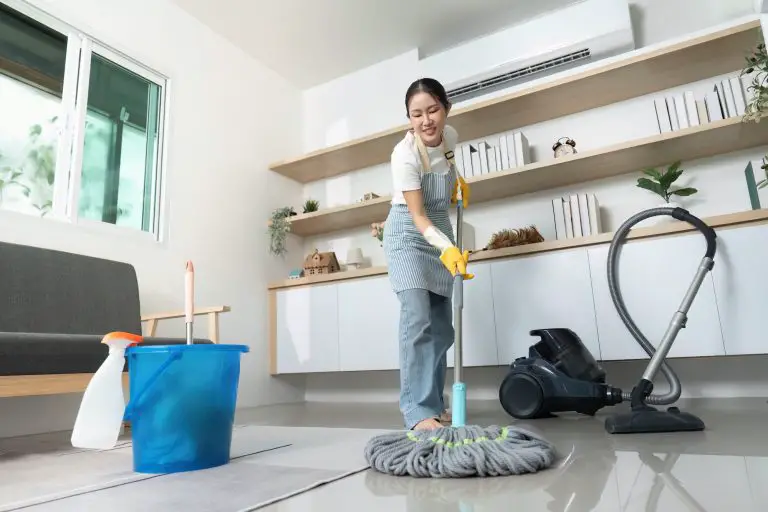 Person cleaning floor with mop and vacuum.