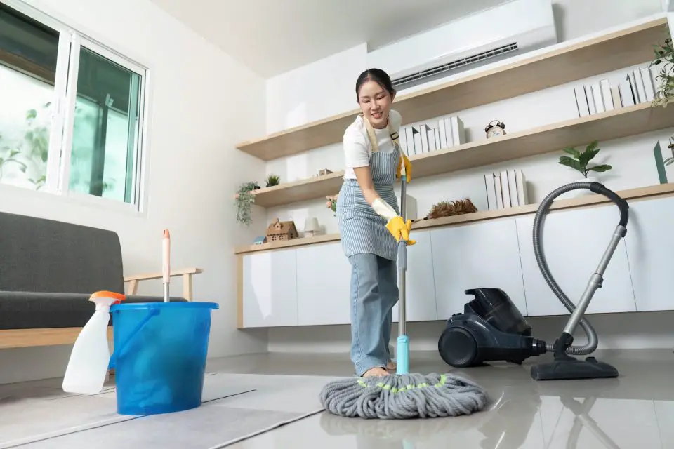 Person cleaning floor with mop and vacuum.
