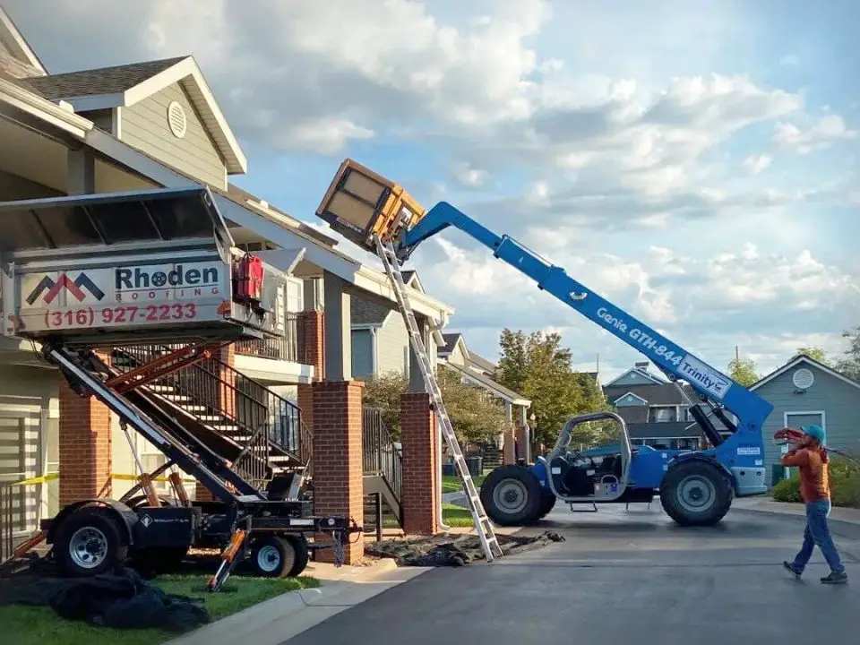 Roofing equipment lifting materials to apartment roof.