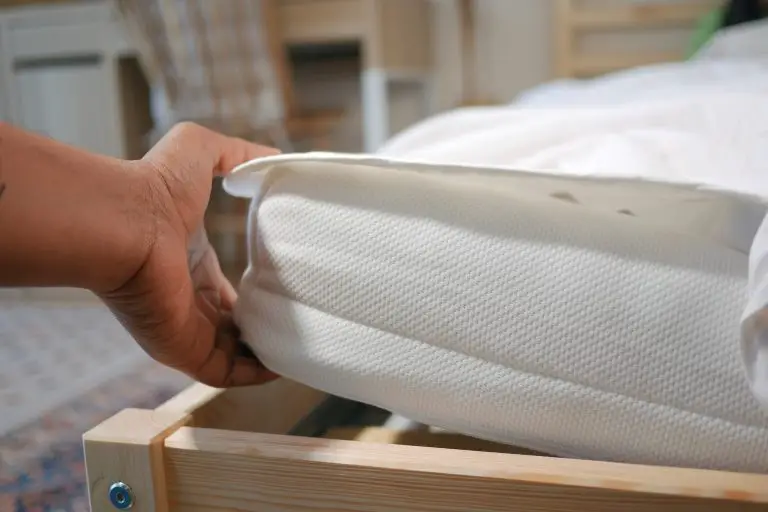 Hand adjusting a white mattress corner.