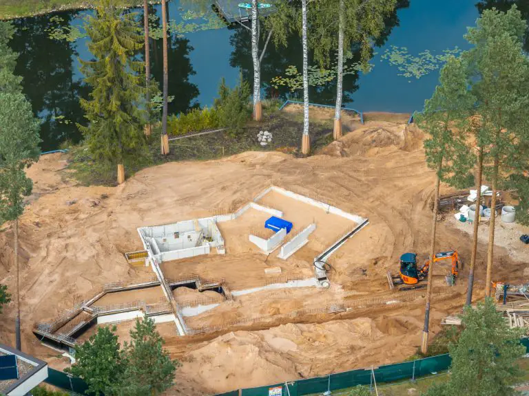 House foundation construction site with nearby pond.