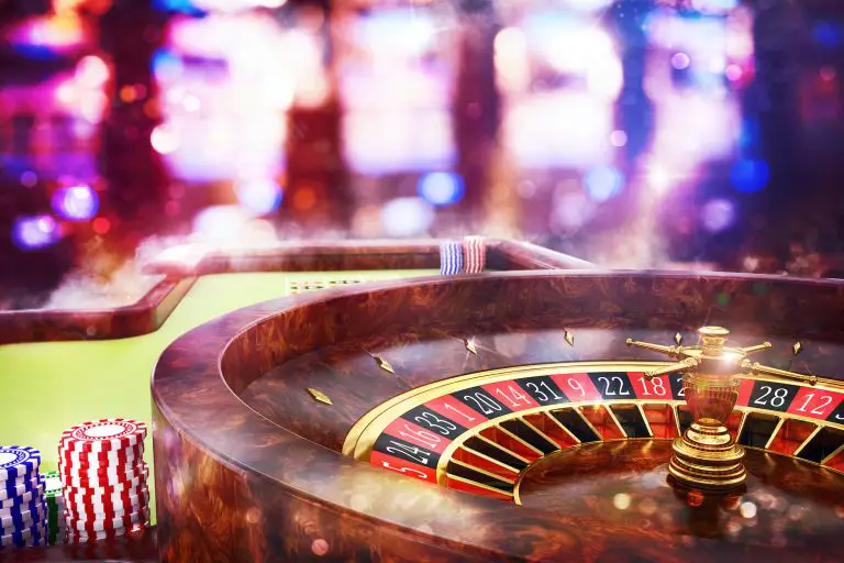 Casino roulette wheel and poker chips on table.